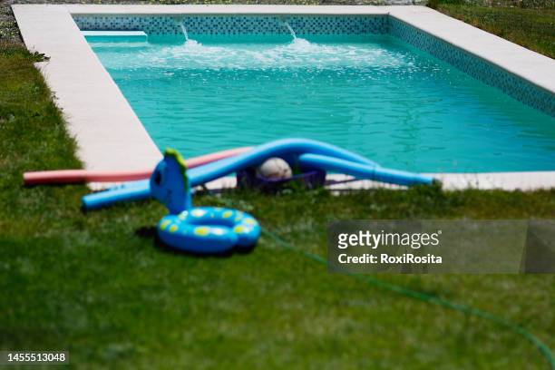 empty pool filling with water. floats in the grass on a sunny day. - plastic pool stockfoto's en -beelden
