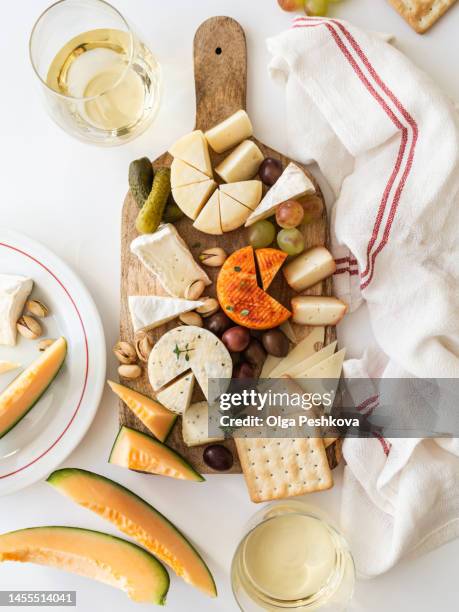 assorted cheeses, crackers, olives, grapes and white wine in glasses on wooden board - brotzeitbrett stock-fotos und bilder