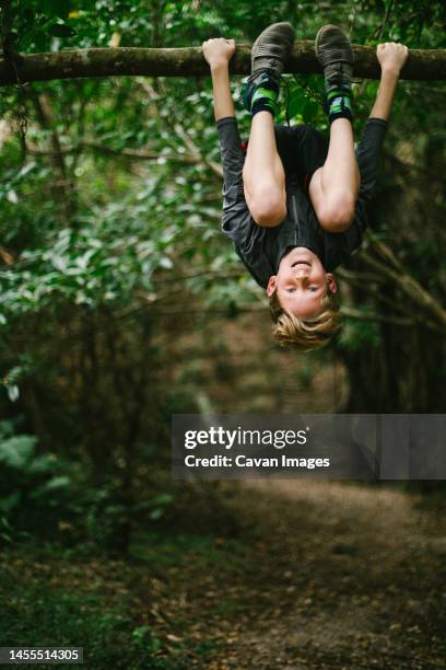 pre teen child boy climbs tree in forest on nature adventure - natural land state stock pictures, royalty-free photos & images