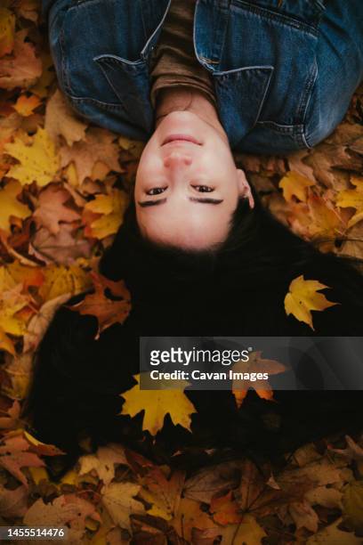 asian japanese young woman in jean jacket lays in fall leaves - walden pond stock pictures, royalty-free photos & images