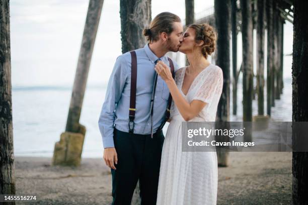 newlyweds kissing together on beach in the redwoods, california, - small wedding fotografías e imágenes de stock