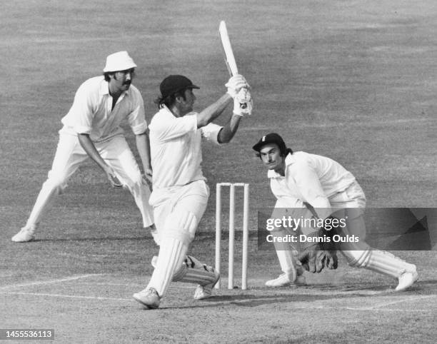 England Wicketkeeper Alan Knott and slip fielder Graham Gooch look on as Australian team captain and batsman Ian Chappell plays a sweep shot off the...