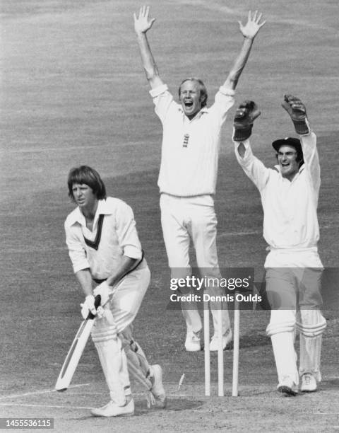 England Wicketkeeper Alan Knott and team captain Tony Greig raise their arms in celebration as Australian batsman Jeff Thomson is bowled out for 17...