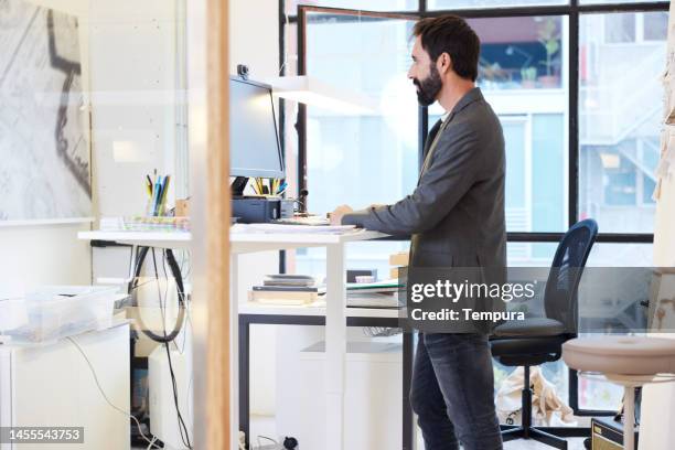 männlicher geschäftsmann arbeitet am stehpult in modernem, gut beleuchtetem büro - ergonomie stock-fotos und bilder