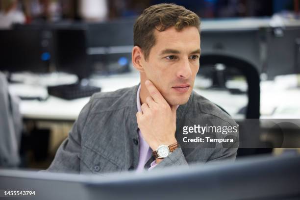 portrait of hardworking mid adult business guy in deep thought at his desk in large open office - wavy hair man stock pictures, royalty-free photos & images