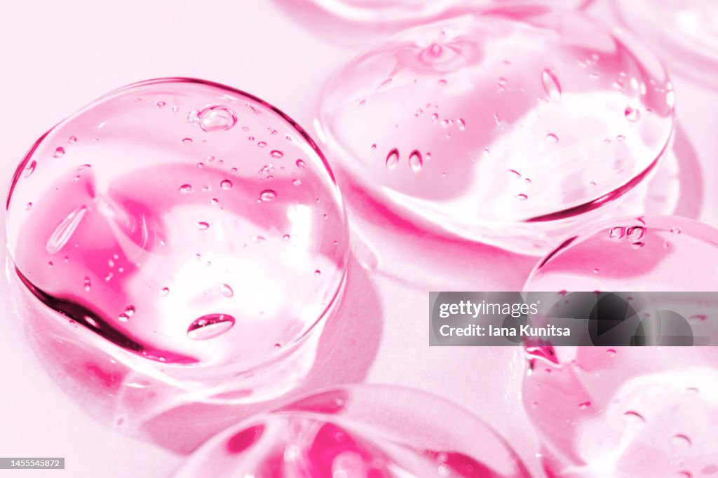 Transparent pink moisture face serum smeared. Hydrating hyaluronic acid. Hair gel with bubbles. Cosmetic products for makeup and skin care. Cosmetology.