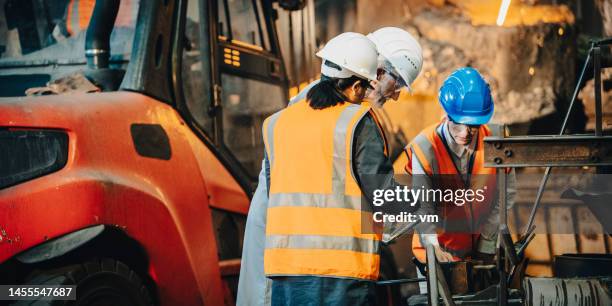 mature adult male engineer explaining process to female visitors in factory - cast iron stock pictures, royalty-free photos & images