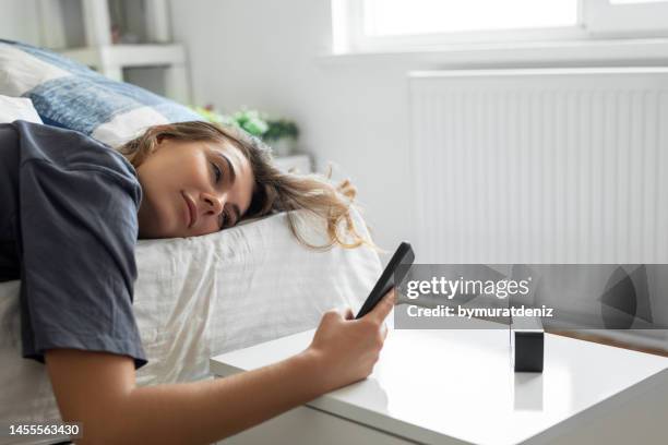 young woman is waking up - alarm clock on nightstand stock pictures, royalty-free photos & images