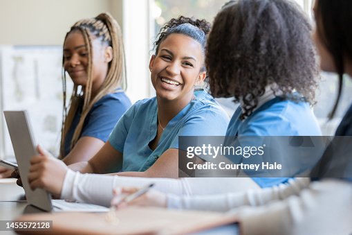 Happy young adult nursing or medical student talks with classmate in university medical training class