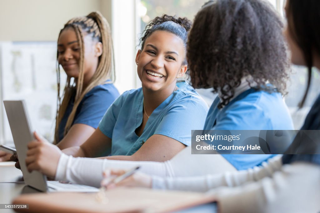 Happy young adult nursing or medical student talks with classmate in university medical training class