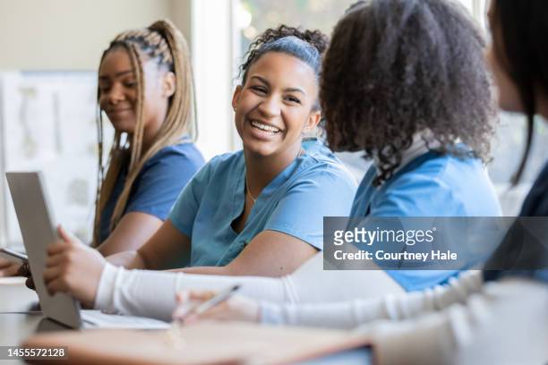 happy young adult nursing or medical student talks with classmate in university medical training class - medical student stock pictures, royalty-free photos & images