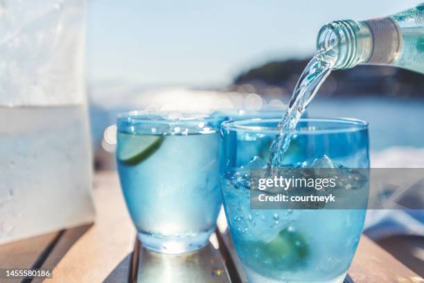 pouring water from a bottle into a glass at the beach. - frisdrank stockfoto's en -beelden