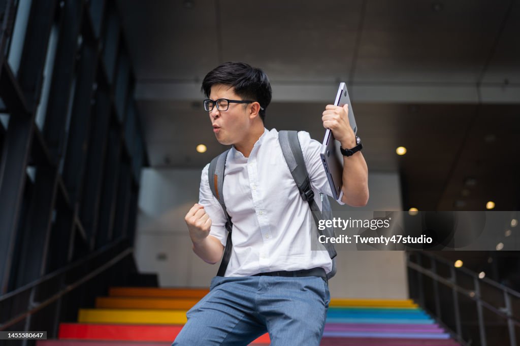 Portrait of success Asian young businessman arm raised