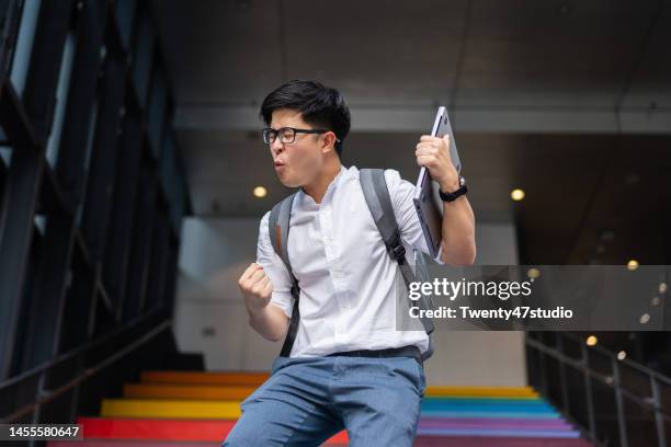 portrait of success asian young businessman arm raised - durchbruch stock-fotos und bilder