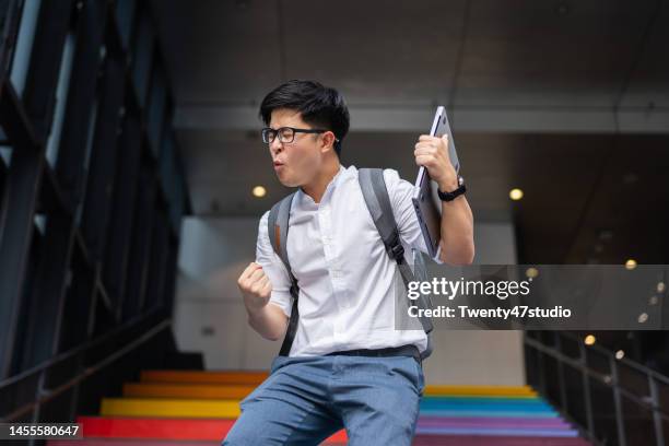 portrait of success asian young businessman arm raised - champion bureau photos et images de collection