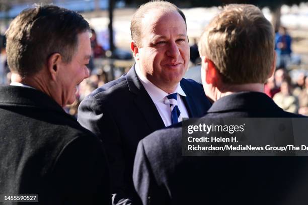 Governor Jared Polis shakes hands with former governor Bill Owens, left, and Senator Michael Bennet, right, during inauguration day on January 10,...