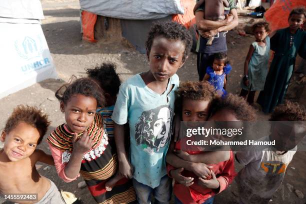 Yemeni displaced children are seen outside their shelters at an internally displaced camp on January 10, 2023 near Amran province, Yemen. According...
