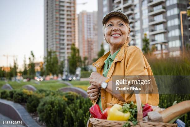 une femme âgée revenant du marché fermier - district photos et images de collection