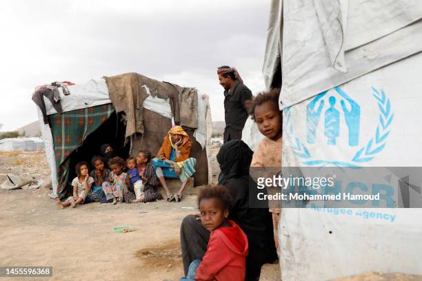 Yemeni displaced families are seen outside their shelters at an internally displaced camp on January 10, 2023 near Amran province, Yemen. According...