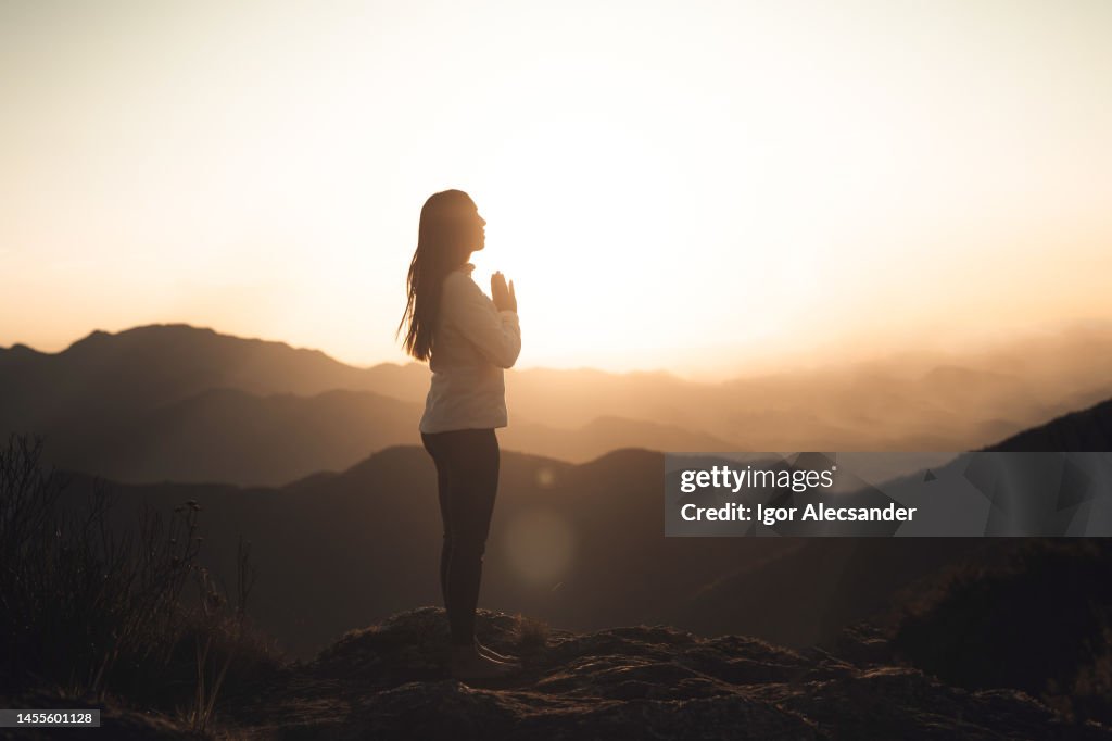 Woman meditating at sunset in the mountains