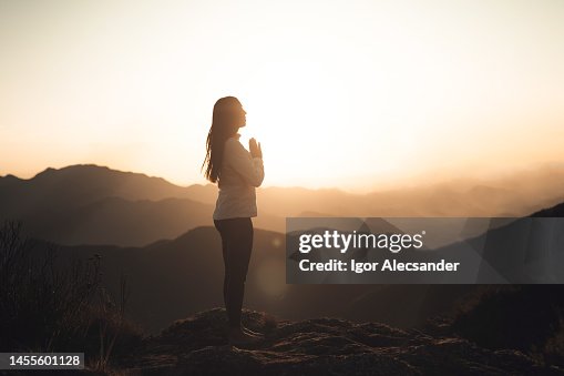 Woman meditating at sunset in the mountains Woman meditating at sunset in the mountains