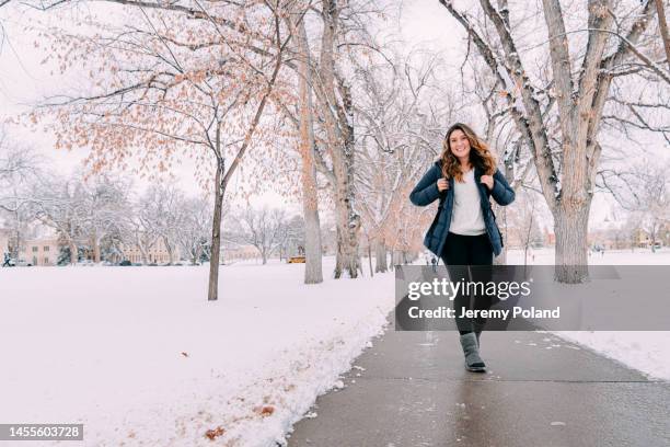 cute portrait with copy space of a cheerful university student walking to class looking at camera on campus on a snowy day in colorado - colorado state university stock pictures, royalty-free photos & images