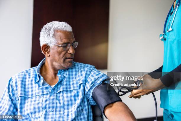 sitzung der krankenschwester mit einem älteren schwarzen männlichen patienten - blood pressure stock-fotos und bilder