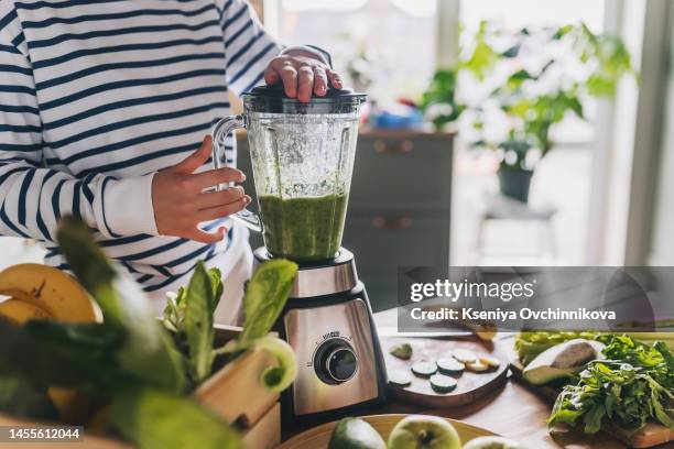healthy eating, cooking, vegetarian food, dieting and people concept - close up of young woman with blender and green vegetables making detox shake or smoothie at home - mixeur photos et images de collection