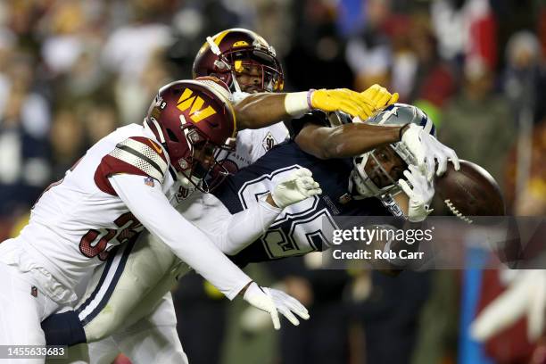 Cornerback Kendall Fuller and safety Jeremy Reaves of the Washington Commanders break up a pass intended for wide receiver Noah Brown of the Dallas...