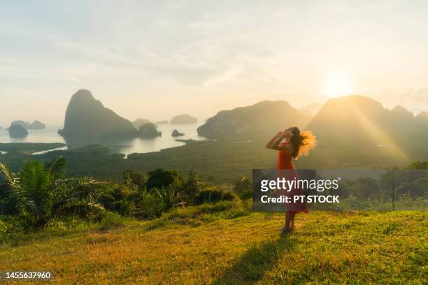 woman in red standing in view of sametnangshe phang nga bay with sea and mountains in phang nga province, thailand - red sea rain stock pictures, royalty-free photos & images