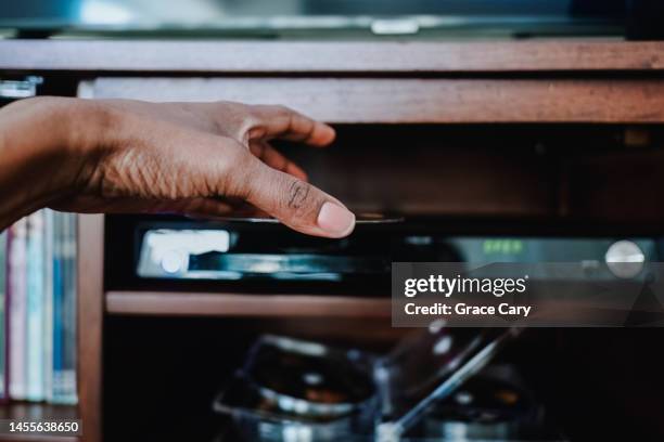 woman inserts disc into dvd player - dvd player stock pictures, royalty-free photos & images