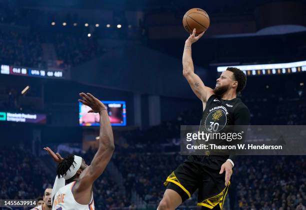 Stephen Curry of the Golden State Warriors shoots over Josh Okogie of the Phoenix Suns during the second quarter at Chase Center on January 10, 2023...