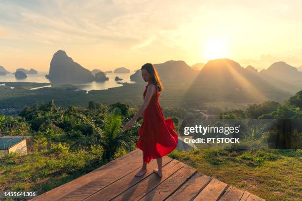 woman in red standing in view of sametnangshe phang nga bay with sea and mountains in phang nga province, thailand - red sea rain stock pictures, royalty-free photos & images