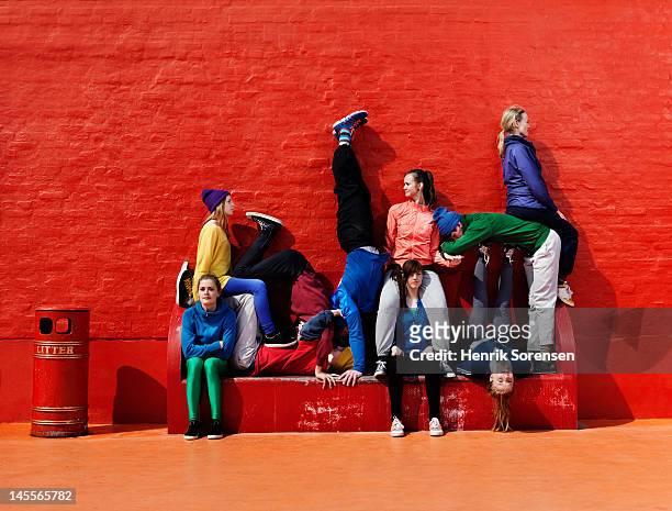 young people sitting and stading on a bench - young adult fotografías e imágenes de stock