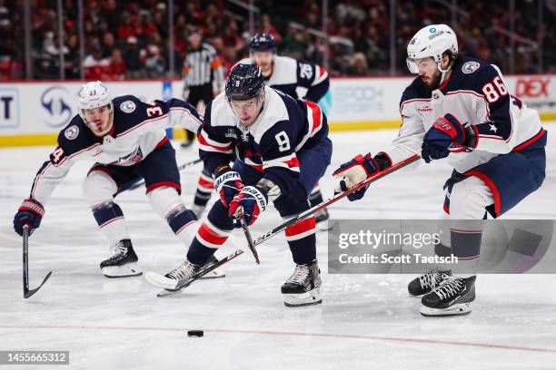 Dmitry Orlov of the Washington Capitals skates with the puck as Cole Sillinger and Kirill Marchenko of the Columbus Blue Jackets defend during the...