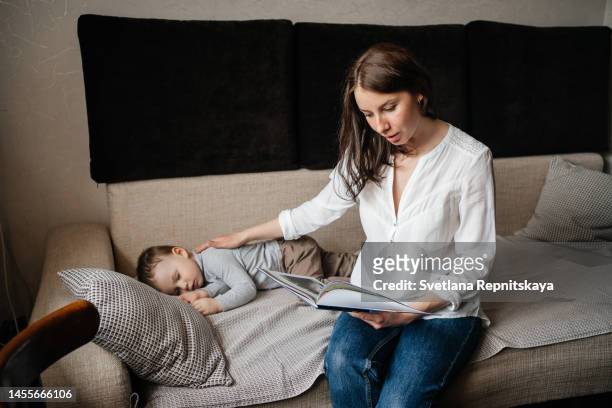 mother reading a book to her child before going to bed - mother sleeping child stock-fotos und bilder