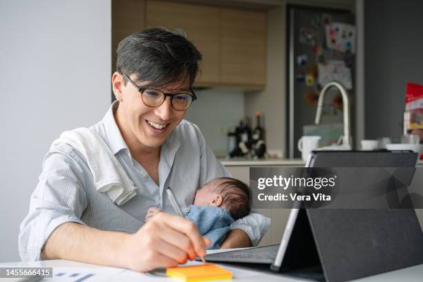 smiling japanese young father working with technology and nursing baby at home - workers compensation - fotografias e filmes do acervo