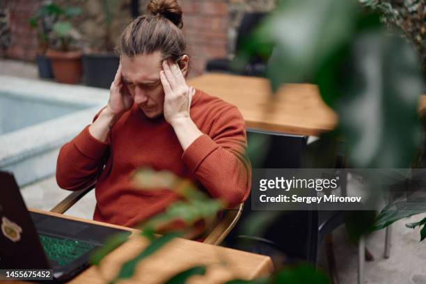 young freelancer man catching headache while working at laptop - georgian man stock pictures, royalty-free photos & images