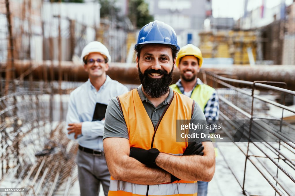 Ingenieure auf der Baustelle, schauen in die Kamera und lächeln. Beschäftigung im Wohnungs- und Immobiliensektor