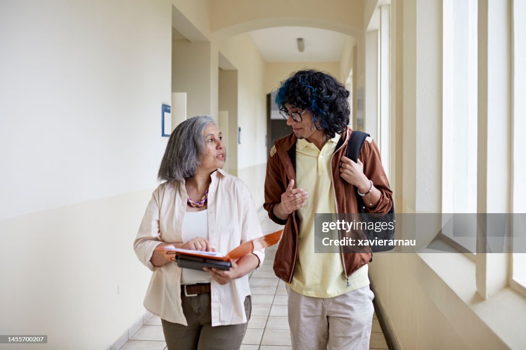 Student and professor walking and talking on campus