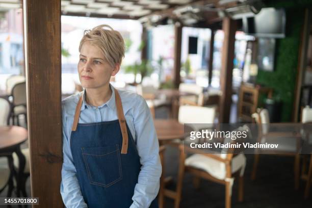 portrait of a restaurant manager standing distraught in the middle of her empty restaurant - restaurant owner stock pictures, royalty-free photos & images