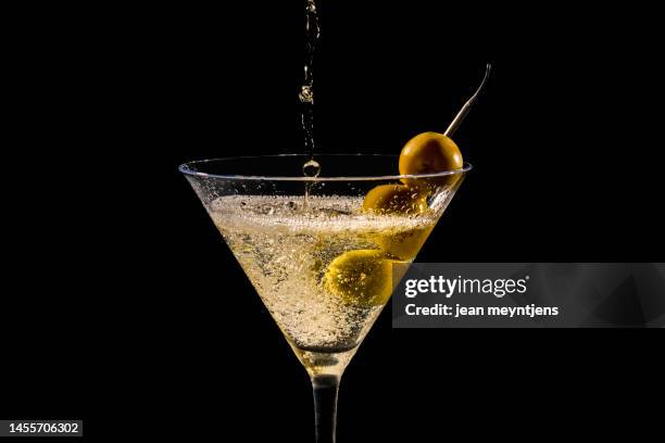 close up of pouring and splashing  martini glass with olives - martini stockfoto's en -beelden