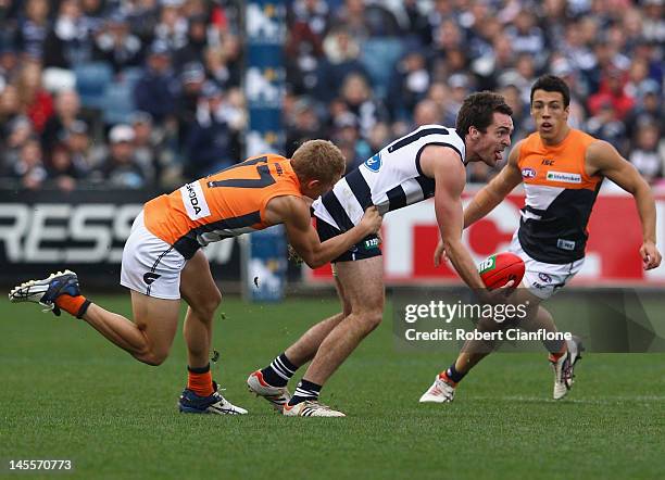 Jesse Stringer of the Cats is pressured by Adam Treloar of the Giants during the round 10 AFL match between the Geelong Cats and the Greater Western...