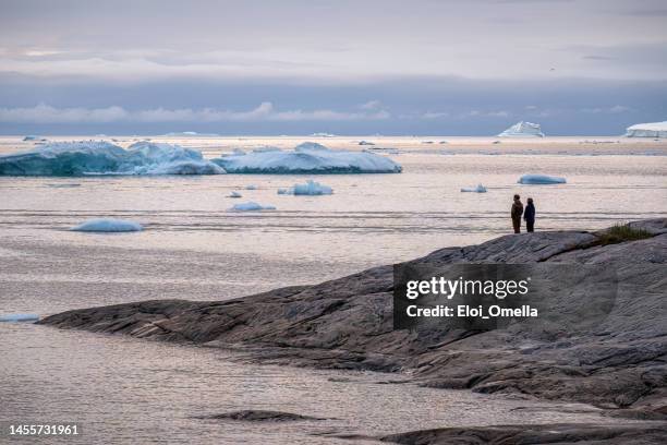 couple relaxing in front of the icebergs in greenland - ilulissat stock pictures, royalty-free photos & images