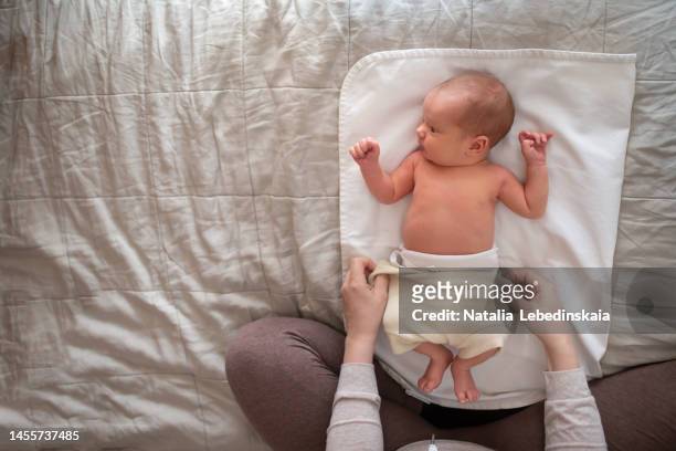 hygiene and care for baby. grandmother changes reusable diaper for newborn on bed. top view. - reusable diaper stock pictures, royalty-free photos & images