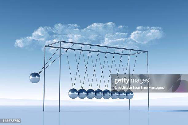 shiny silver newton's cradle in front and blue sky - newtons cradle stockfoto's en -beelden