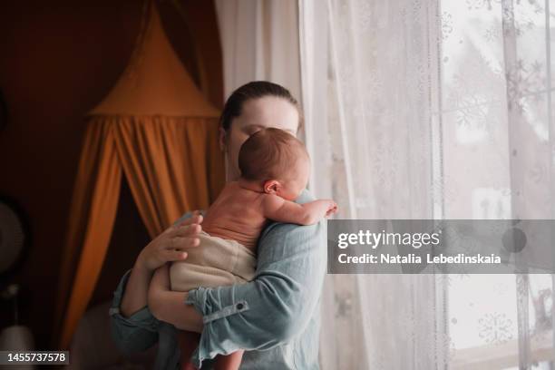 mature mother comforting her newborn while crying. - babies only in cloth diapers stock-fotos und bilder