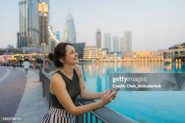 woman holding smartphone while exploring dubai - dubai tourist stock pictures, royalty-free photos & images