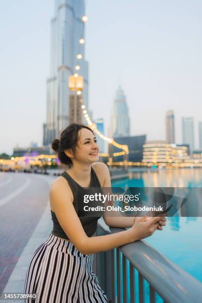 woman holding smartphone while exploring dubai - middle east business people stock pictures, royalty-free photos & images