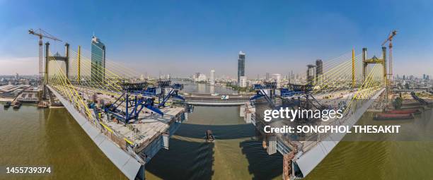 aerial view/a suspension bridge over the river is being built to connect the city. - ship's bridge foto e immagini stock